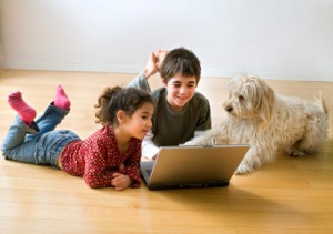two kids with laptop computer and a dog